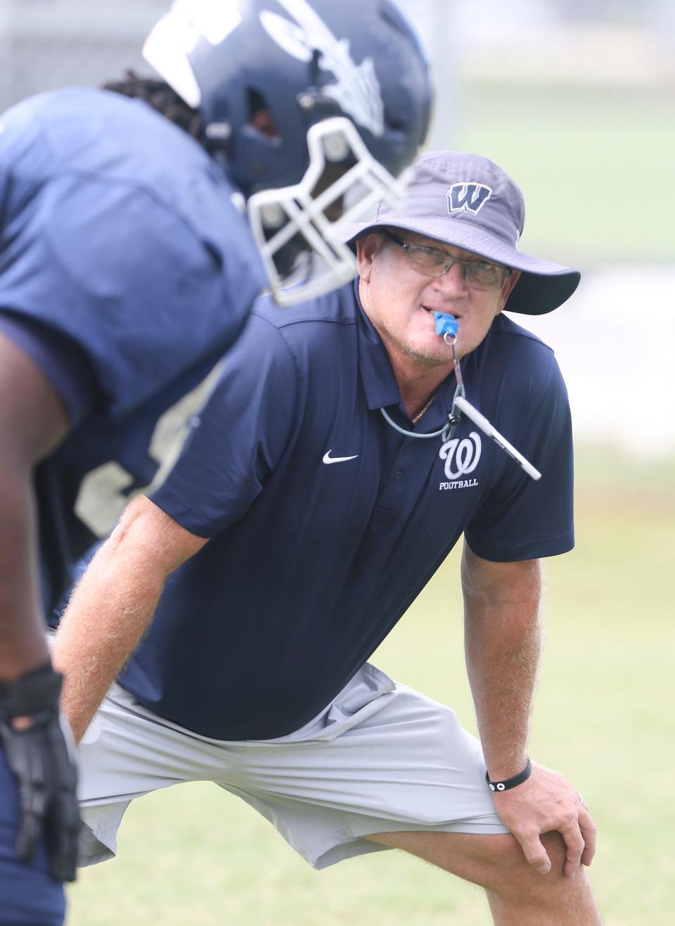 Head coach Keith White watches over his offensive line workout during a Walton Braves summer football practice.