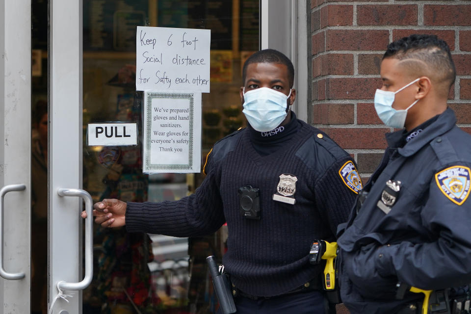 Officials walk into a store that has a "Social Distancing" sign on the door during the outbreak of coronavirus disease (COVID-19), in the Manhattan borough of New York City