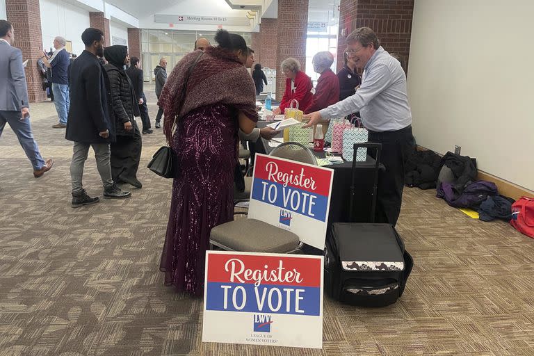 Las personas se acercan a una mesa donde pueden registrarse para votar después de convertirse en ciudadanos estadounidenses.