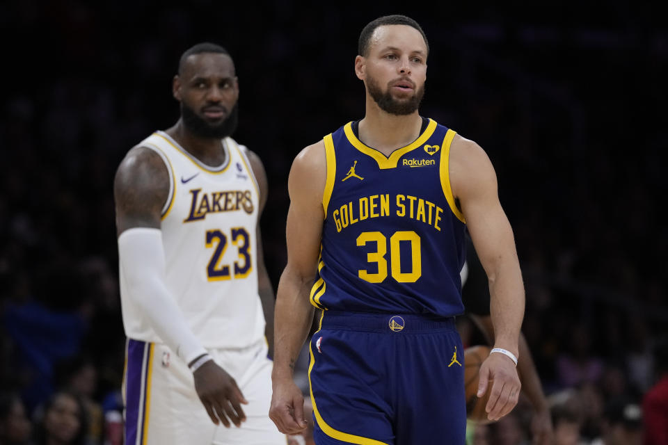 Golden State Warriors guard Stephen Curry (30) and Los Angeles Lakers forward LeBron James (23) react after play was stopped due to a shot clock malfunction during the second half of an NBA basketball game against the Golden State Warriors in Los Angeles, Saturday, March 16, 2024. (AP Photo/Ashley Landis)