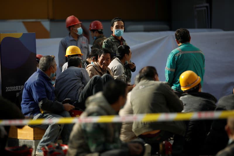 Construction workers wearing masks following the coronavirus disease (COVID-19) outbreak gather on a street in Beijing