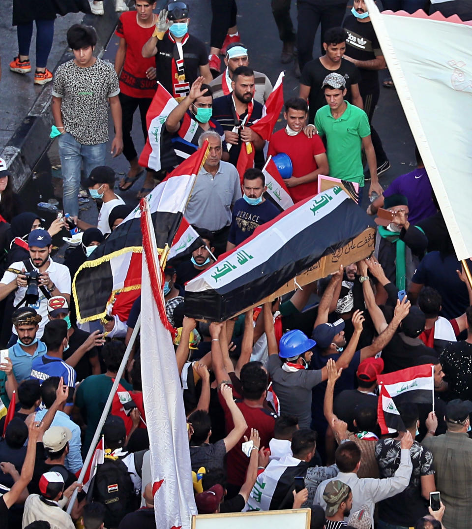 In this Thursday, Oct. 31, 2019 photo, mourners and protesters carry the flag-draped coffin of Mohammed Sadiq during his funeral during a demonstration at Tahrir Square in Baghdad, Iraq. Sadiq was killed while participating in the anti-government ongoing protests, his family said. (AP Photo/Hadi Mizban)