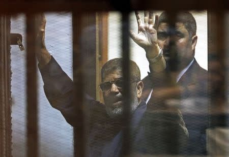 Deposed Egyptian President Mohamed Mursi greets his lawyers and people from behind bars after his verdict at a court on the outskirts of Cairo, Egypt June 16, 2015. REUTERS/Asmaa Waguih