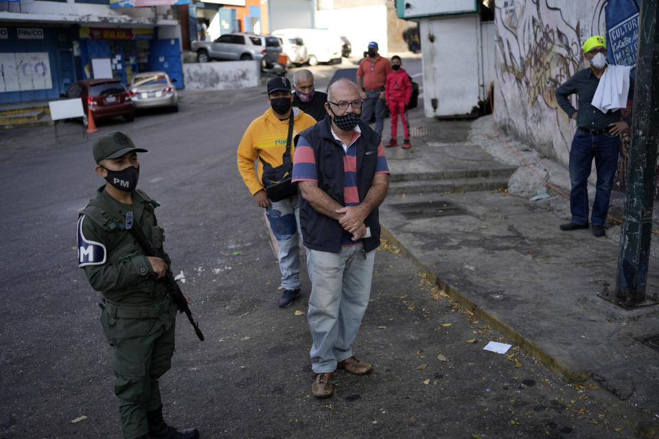 People line up at a site set up by the National Election Council (CNE) where people can sign a petition in favor of holding a referendum to remove President Nicolas Maduro from office in Caracas, Venezuela, Wednesday, Jan. 26, 2022. The signatures of 20 percent of registered voter must be collected within 12 hours to request a presidential recall, a CNE rule that Maduro's opposition criticizes as impossible. (AP Photo/Matias Delacroix)