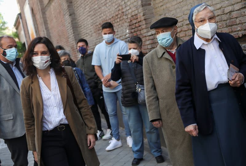 La dirigente de la Comunidad de Madrid y candidata del Partido Popular (PP), Isabel Díaz Ayuso, pasa por delante de una cola en el exterior de un colegio electoral tras depositar su voto durante las elecciones autonómicas de Madrid