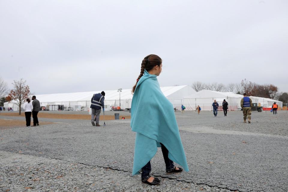 A girl stands outside wearing a blanket over her clothing