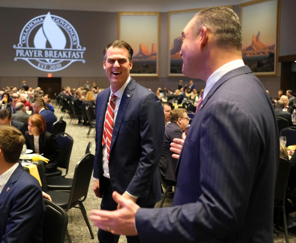 Gov. Kevin Stitt, left, and Speaker of the House Charles McCall laugh Tuesday after Stitt showed him a photo on his phone at the Governor's Prayer Breakfast, coordinated by the nonprofit Capitol Culture, at the National Cowboy & Western Heritage Museum.