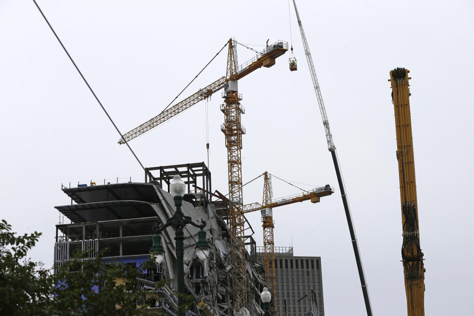 Workers in a bucket begin the process of planting explosive charges on two unstable cranes at the Hard Rock Hotel, which underwent a partial, major collapse Saturday, Oct. 12, in New Orleans, viewed Thursday, Oct. 17, 2019. Authorities say explosives will be strategically placed on the two unstable construction cranes in hopes of bringing them down with a series of small controlled blasts ahead of approaching tropical weather. Officials hope to bring the towers down Friday without damaging nearby businesses and historic buildings in and around the nearby French Quarter. (AP Photo/Gerald Herbert)