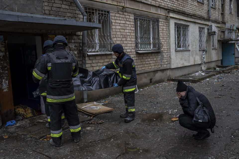 Lilia Kristenko, 38, cries as city responders collect the dead body of her mother Natalia Kristenko in Kherson, southern Ukraine, Friday, Nov. 25, 2022. Natalia Kristenko's dead body lay covered in a blanket in the doorway of her apartment building for hours overnight. The 62-year-old woman had walked outside her home with her husband Thursday evening after drinking tea when the building was struck. Kristenko was killed instantly from a wound to the head. Her husband died hours later in the hospital from internal bleeding. (AP Photo/Bernat Armangue)