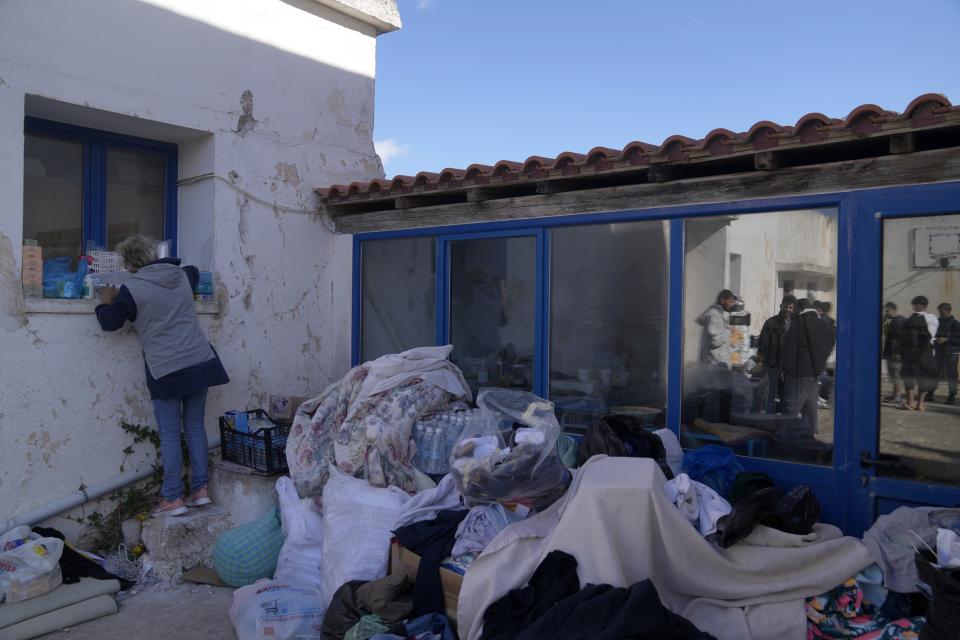 A volunteer adjusts the supplies for the migrants at an old school used as a temporary shelter on the island of Kythira, southern Greece, Friday, Oct. 7, 2022. Strong winds were hampering rescue efforts at two Greek islands Friday for at least 10 migrants believed to be missing after shipwrecks left more than 20 people dead, officials said. (AP Photo/Thanassis Stavrakis)