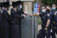 Members of the Orthodox Jewish community speak with NYPD officers, Wednesday, Oct. 7, 2020, in the Borough Park neighborhood of the Brooklyn borough of New York. Gov. Andrew Cuomo moved to reinstate restrictions on businesses, houses of worship and schools in and near areas where coronavirus cases are spiking. Many neighborhoods that stand to be affected are home to large enclaves of Orthodox Jews. (AP Photo/John Minchillo)