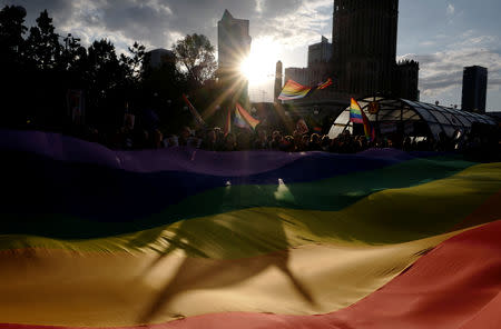 People hold a large rainbow flag during a protest in support of Elzbieta Podlesna, the author of an image depicting the Virgin Mary with a rainbow-coloured halo, reminiscent of the LGBT flag, who was detained for offending religious beliefs, in Warsaw, Poland May 7, 2019. REUTERS/Kacper Pempel