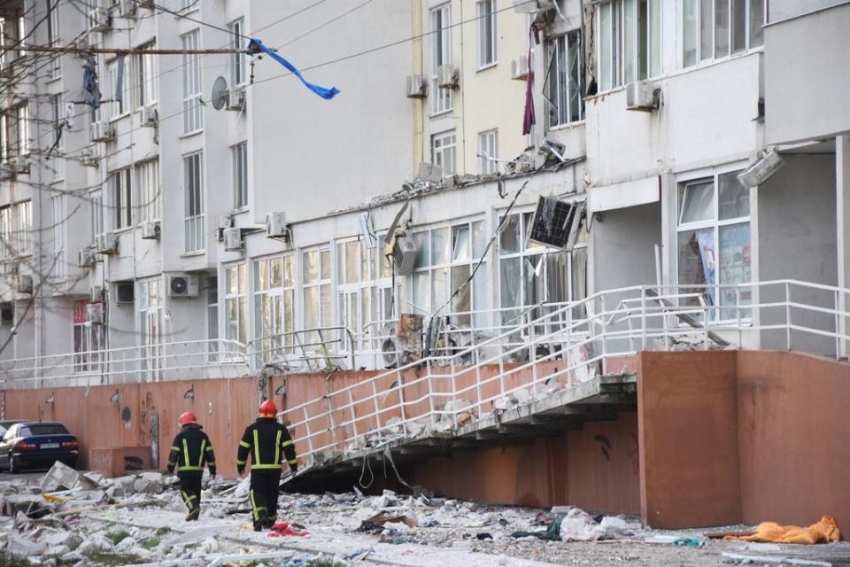 Firefighters walk past an apartment building damaged by Russian shelling (AP)