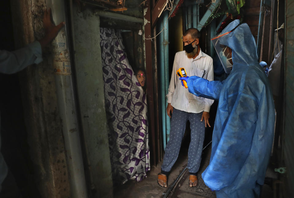 A doctor checks the temperature of a girl in Dharavi, one of Asia's largest slums, during lockdown to prevent the spread of the coronavirus in Mumbai, India. Monday, April 13, 2020. (AP Photo/Rafiq Maqbool, file)