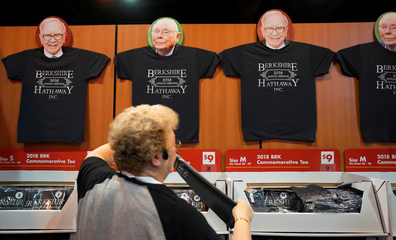 A worker arranges a display of t-shirts with images of Warren Buffett and Charlie Munger at the Berkshire Hathaway Inc annual meeting, the largest in corporate America, in its hometown of Omaha, Nebraska. REUTERS/Rick Wilking