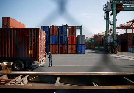 A man works between shipping containers at a port in Tokyo, Japan, March 22, 2017. REUTERS/Issei Kato