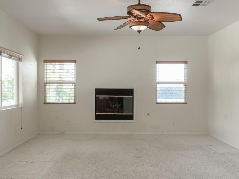 An empty living room with a fireplace built into the wall.