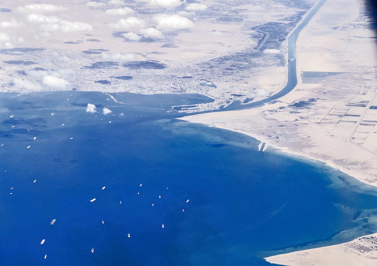 An aerial view taken on March 27, 2021, from the porthole of a commercial plane shows stranded ships waiting in in the Gulf of Suez to cross the Suez Canal at its southern entrance near the Red Sea port city of Suez, as the waterway remains blocked by the Panama-flagged container ship "MV Ever Given."