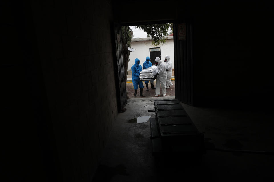 Workers wearing protective gear carry the plastic-wrapped coffin of a person who died from COVID-19 into the crematorium at San Cristobal Mausoleums in Ecatepec, Mexico State, part of the Mexico City metropolitan area, Thursday, May 21, 2020. (AP Photo/Rebecca Blackwell)