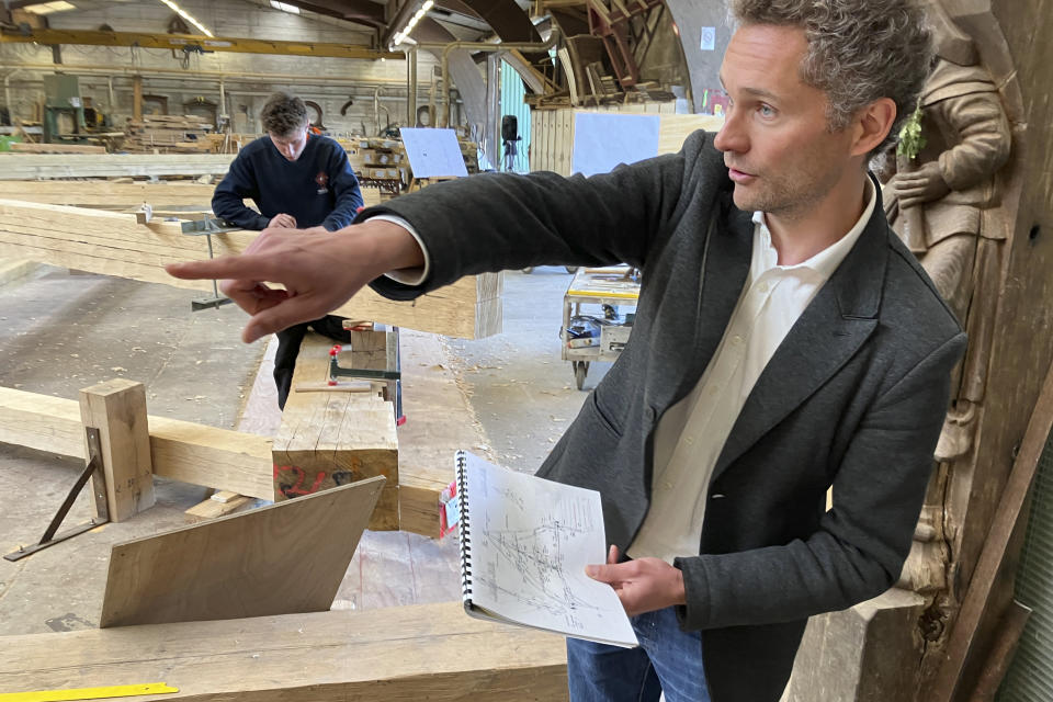 Chief architect Remi Froment holds the drawings of the Notre Dame de Paris cathedral he made in 2012 which are being used in part as the basis for the rebuilding the roof, Thursday, May, 25, 2023, near Angers, western France. Carpenters building a new timber frame for the fire-ravaged roof of Paris' Notre Dame Cathedral are using the same tools and techniques as their medieval predecessors. For them, working with hand-axes to fashion oak beams has been like stepping back in time. (AP Photo/Jeffrey Schaeffer)