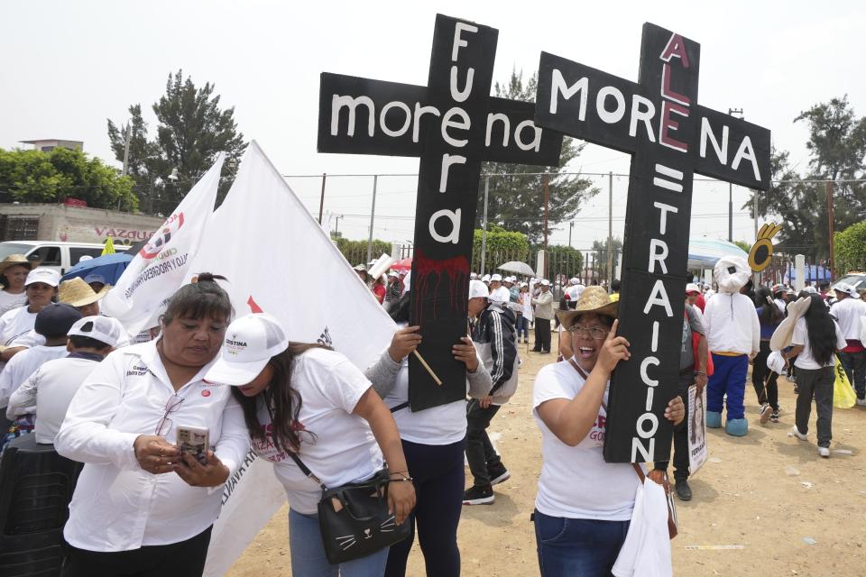 Supporters of the presidential candidate Xóchitl Galvez hold crosses that read in Spanish "Get out Morena, Morena treason," referring to the ruling party, during Galvez's campaign rally in Los Reyes la Paz, Wednesday, May 29, 2024. Mexico's general election is set for June 2. (AP Photo/Fernando Llano)