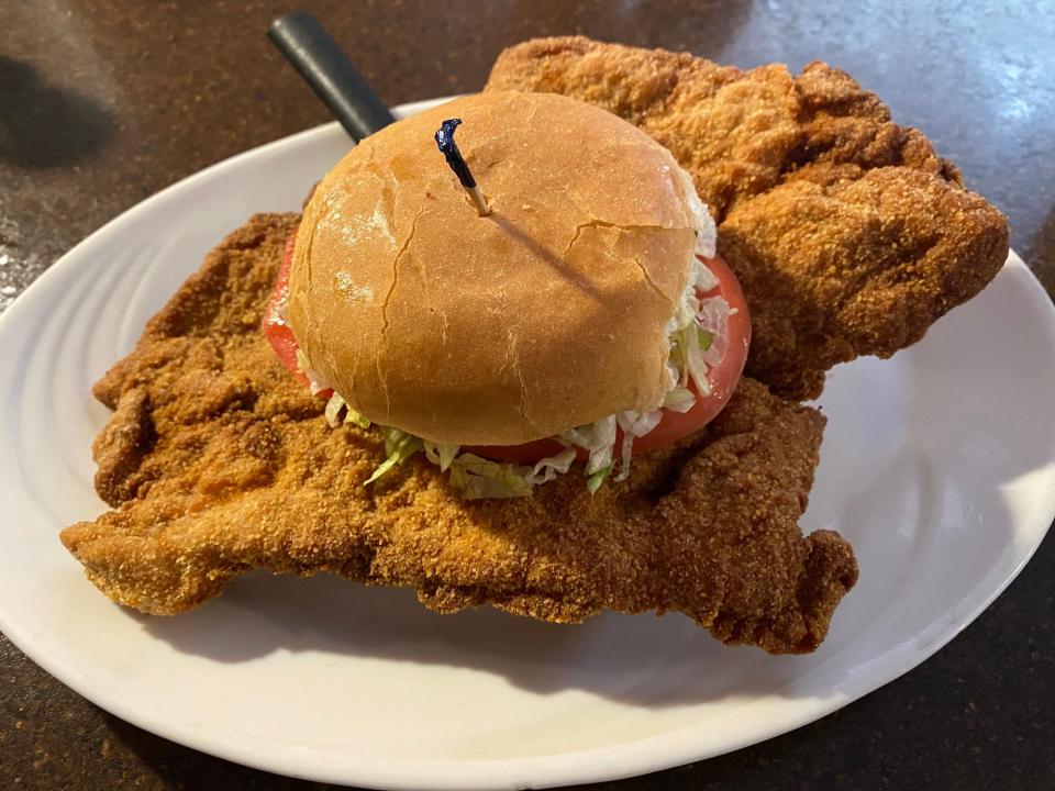 pork tenderloin sandwich with tomato and lettuce on a white plate