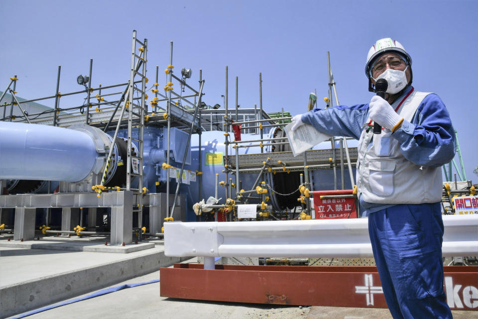 An employee of Tokyo Electric Power Company explains about the facility to be used to release treated radioactive water to media at Fukushima Daiichi nuclear power plant in Fukushima, northern Japan, Monday, June 26, 2023. All equipment needed for the release into the sea of treated radioactive wastewater from the wrecked Fukushima nuclear plant has been completed and will be ready for a safety inspection by Japanese regulators this week, the plant operator said Monday, as opposition to the plan continues in and outside Japan over safety concerns.(Kyodo News via AP)