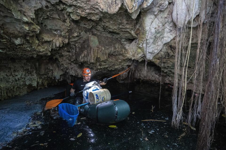 Biologist Roberto Rojo paddles through a cenote while collecting trash, in Playa del Carmen, Mexico, Saturday, March 2, 2024. Construction of the Maya Train is rapidly destroying much of the hidden underground world of caverns and sinkhole lakes, known as cenotes, already under threat by development and mass tourism. (AP Photo/Rodrigo Abd)