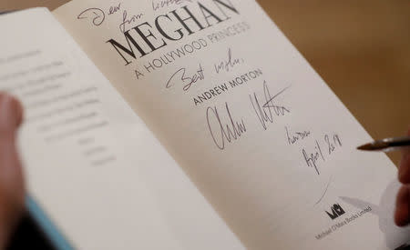 Royal biographer Andrew Morton signs a copy of his latest book, a biography of Meghan Markle, following an interview with Reuters journalists in London, Britain April 9, 2018. REUTERS/Peter Nicholls