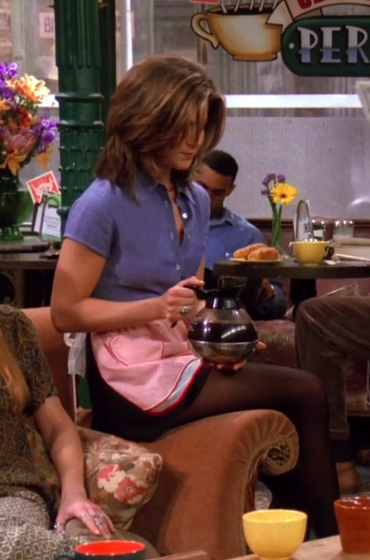 Rachel wearing a short-sleeve button-up, an apron, a miniskirt, and tights