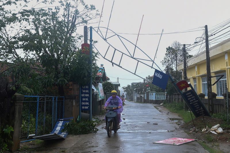 Man bikes past a broken sign as the Typhoon Molave lashes Vietnam's coast in Binh Chau village