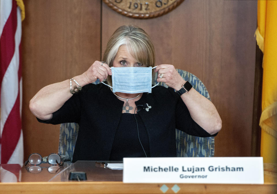 La gobernadora de Nuevo México Michelle Luján Grisham se coloca una mascarilla durante una sesión informativa acerca del coronavirus el 15 de abril de 2020 en Santa Fe, Nuevo México. Luján Grisham ofrece credenciales importantes en caso de que Joe Biden decida lleva a una hispana como compañera de fórmula. (Eddie Moore/The Albuquerque Journal vía AP, Pool, Archivo)