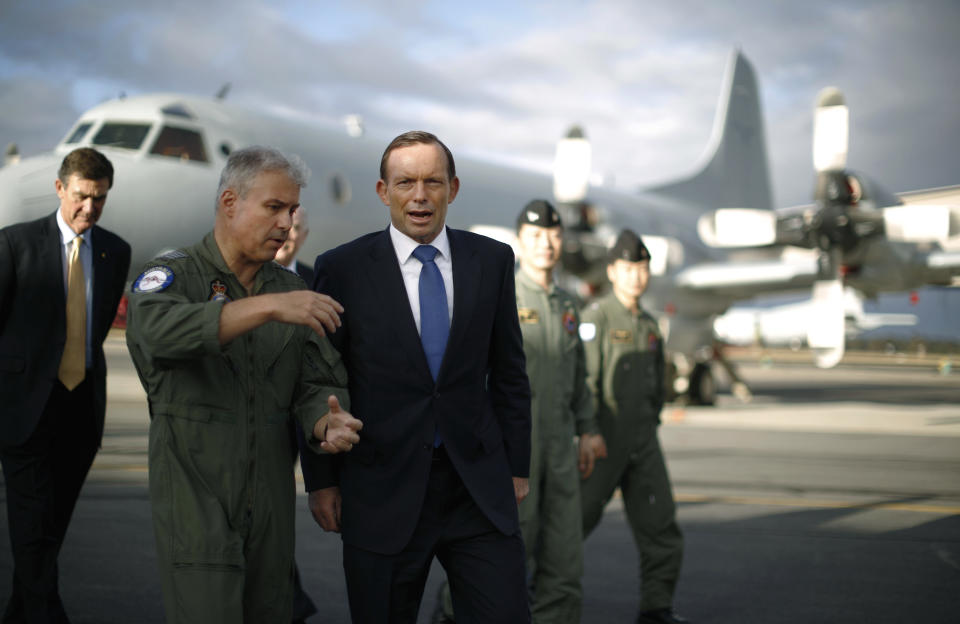 Australian Prime Minister Tony Abbott is guided around a Royal Australian Air Force P-3C Orion aircraft by Australian Air Force Group Commander Craig Heap, second from left, during Abbott's visit to RAAF Base Pearce in Bullsbrook, near Perth, Australia, Monday, March 31, 2014. Abbott said the search for Malaysia Airlines Flight 370 is "an extraordinarily difficult exercise" but that it will go on as long as possible. Abbott said Monday that although no debris has been found in the southern Indian Ocean that can be linked to the plane missing for more than three weeks, the searchers are "well, well short" of any point where they would scale the hunt back. (AP Photo/Jason Reed, Pool)