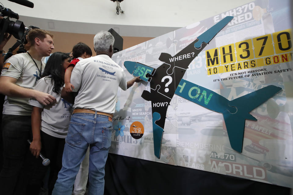 Family members and relatives of passengers on board of the missing Malaysia Airlines Flight 370 stick the jigsaw puzzle board on to the poster during the tenth annual remembrance event at a shopping mall, in Subang Jaya, on the outskirts of Kuala Lumpur, Malaysia, Sunday, March 3, 2024. Ten years ago, a Malaysia Airlines Flight 370, had disappeared March 8, 2014 while en route from Kuala Lumpur to Beijing with over 200 people on board. (AP Photo/FL Wong)