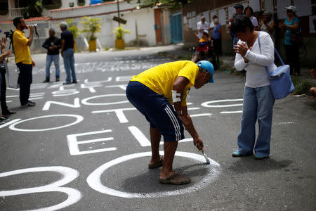 An opposition supporter paints on the road outside a school during a rally against the National Constituent Assembly, outside a school where a polling center will be established for a Constitutional Assembly election next Sunday, in Caracas, Venezuela, July 24, 2017. REUTERS/Andres Martinez Casares