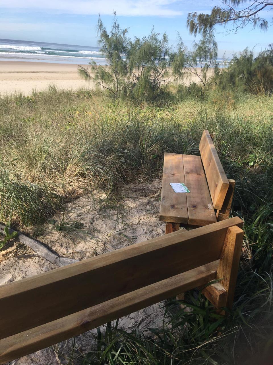 Photo shows two benches facing the beach, one has a sticker put on it by council saying it is waste. Source: Supplied