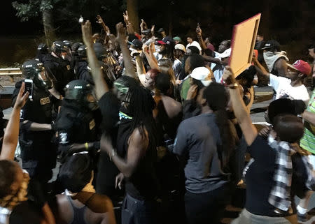 Protestors demonstrate in front of police officers wearing riot gear after police fatally shot Keith Lamont Scott in the parking lot of an apartment complex in Charlotte, North Carolina, U.S. September 20, 2016. REUTERS/Adam Rhew/Charlotte Magazine