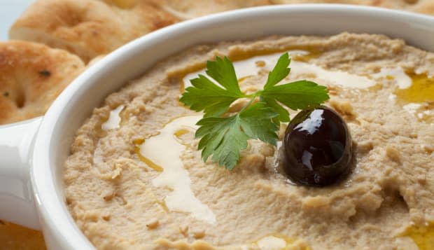 Hummus topped with olive oil, sesame seeds, parsley and an olive, served with Lebanese bread.