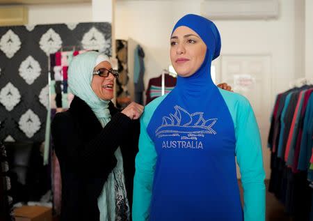 Aheda Zanetti (L), designer of the Burkini swimsuit, adjusts one of the swimsuits on model Salwa Elrashid at her fashion store in Sydney, August 23, 2016. REUTERS/Jason Reed