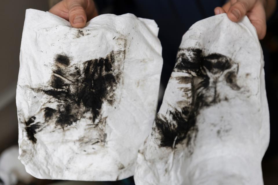 Linehan holds up the paper towels that were used to remove the biological growth from the HVAC unit.