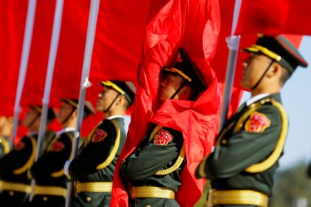 Honour guards hold red flags as they stand at attention before a welcoming ceremony for Japanese Prime Minister Shinzo Abe in Beijing