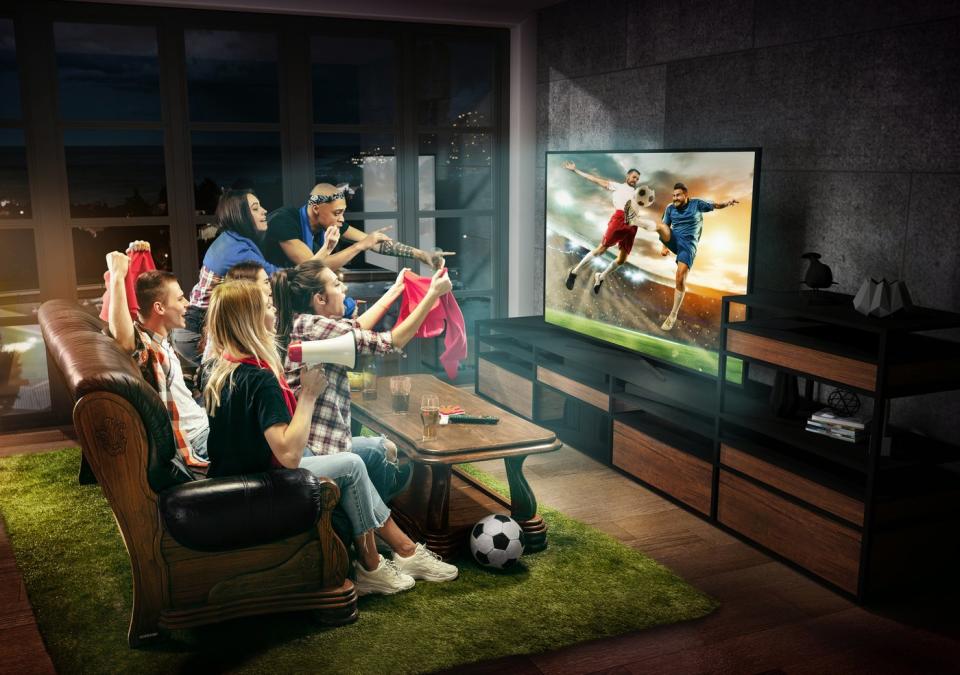 People watching a soccer game on TV from their living room. 