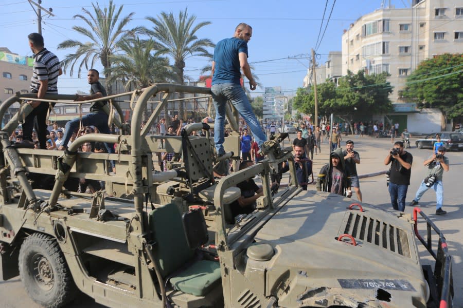 Palestinians ride on an Israeli military vehicle taken by an army base overrun by Hamas militants near the Gaza Strip fence, in Gaza City, Saturday, Oct. 7, 2023. (AP Photo/Abed Abu Reash)