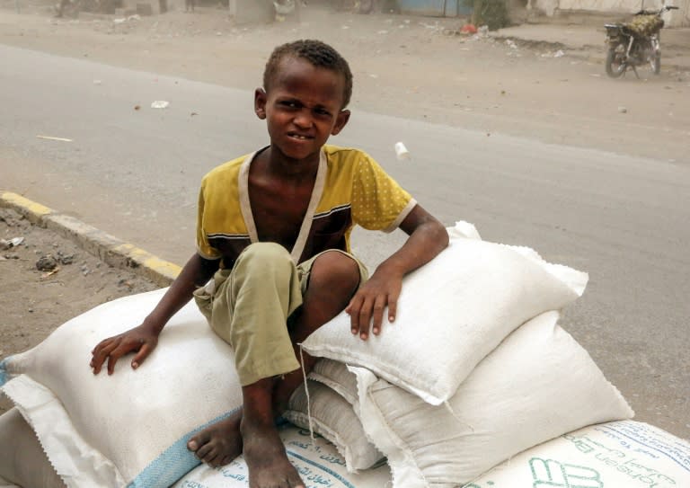 A Yemeni child sits on sacks of desperately neeed food aid in the port city of Hodeidah on June 14, 2018