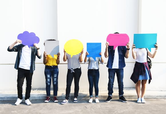 Six people hold cardboard speech and thought bubbles.