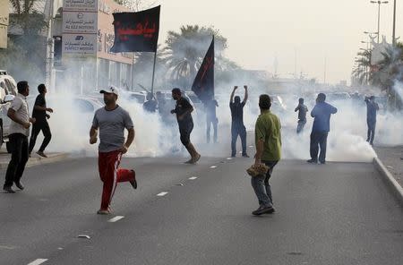 Protesters run from tear gas released by riot police to disperse them, during a march by Shi'ite Muslims in the village of Sanabis west of Manama, Bahrain, to show solidarity for victims of a suicide bomb attack in Saudi Arabia, May 23, 2015. REUTERS/Hamad I Mohammed