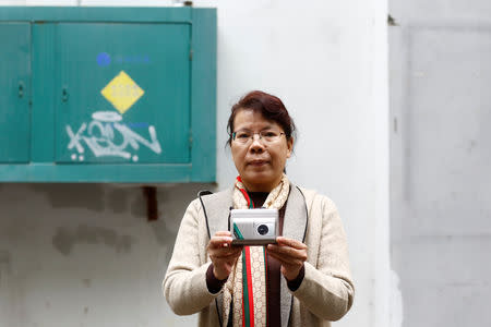 Former employee Huang Caining poses with a Sanyo casette player she used to help make, in front of the Sanyo electronics factory where she worked since 1987, in the Shekou area of Shenzhen, Guangdong Province, China, December 14, 2018. "I came here to see the world. When I signed a three-year contract, I thought I would return home after it ended," Huang said. "Who could have thought that I would end up spending my entire youth here, meeting my significant other, settling down, buying a house and watching our kid coming to this world," she said adding that she would have had none of those opportunities had she stayed in her provincial home town. Picture taken December 14, 2018. REUTERS/Thomas Peter