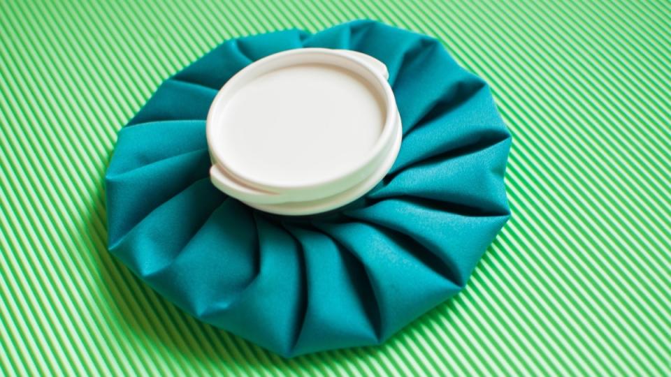 A teal ice pack, which is used for conjunctivitis self-care, against a green background