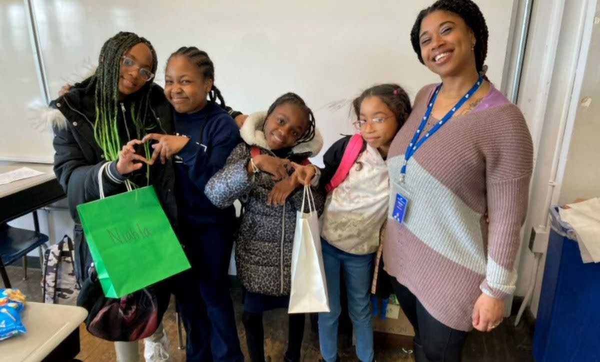 students forming hearts with their hands posing with teacher