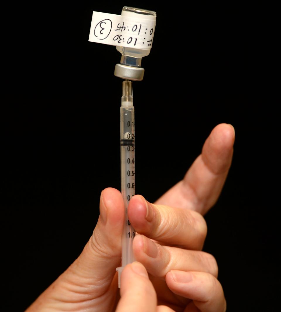 A pharmacist readies a COVID-19 vaccination to be administered.